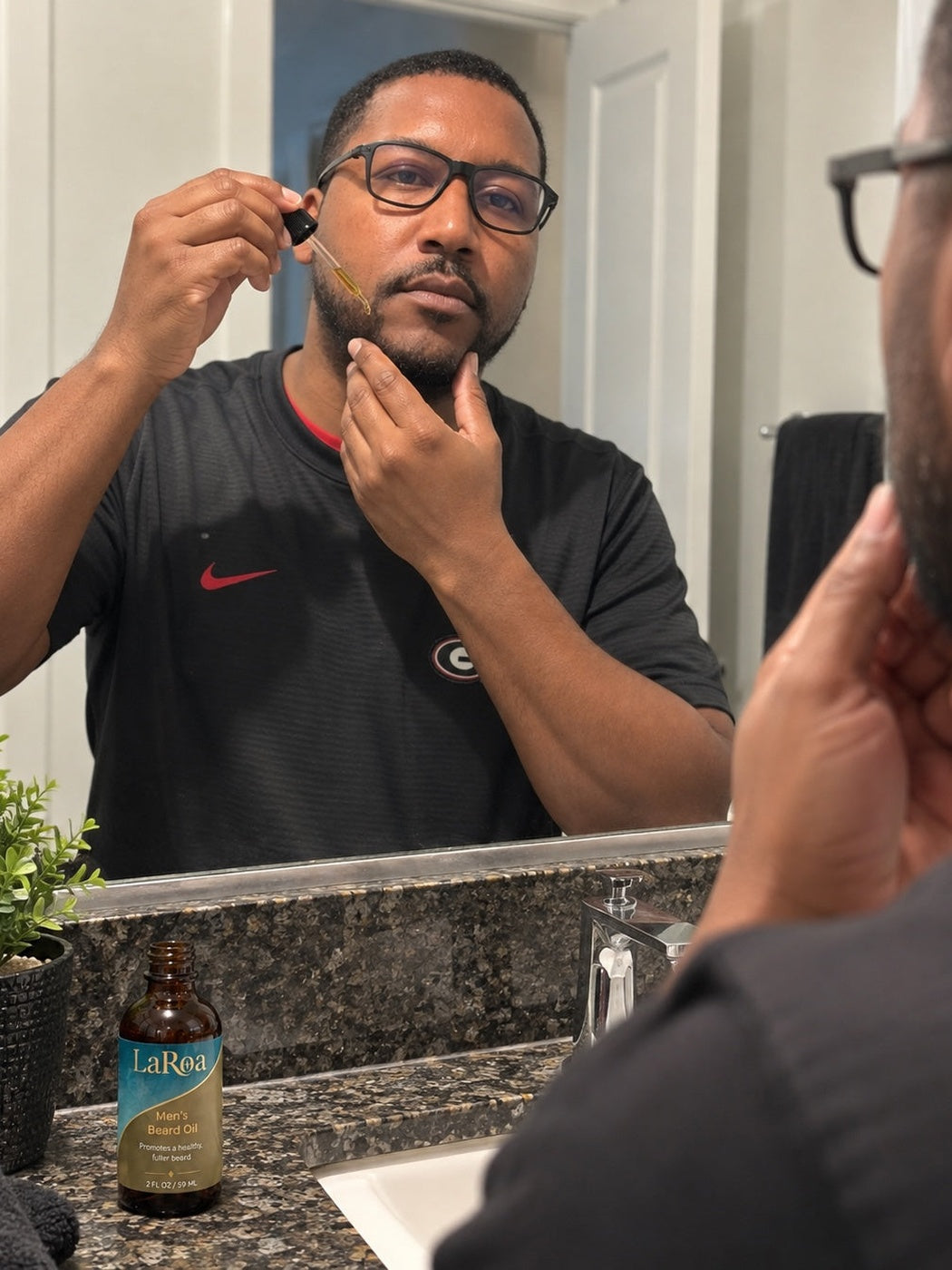 Man applying LaRoa beard oil at a bathroom mirror